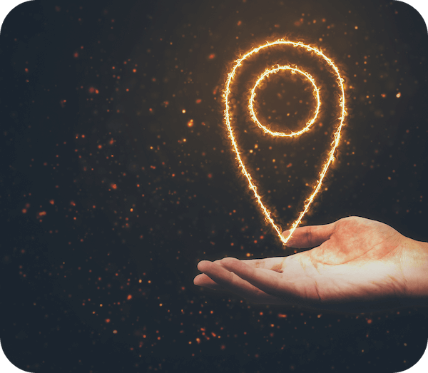 A hand is held palm-up with a location flag made of orange particles hovering over it.