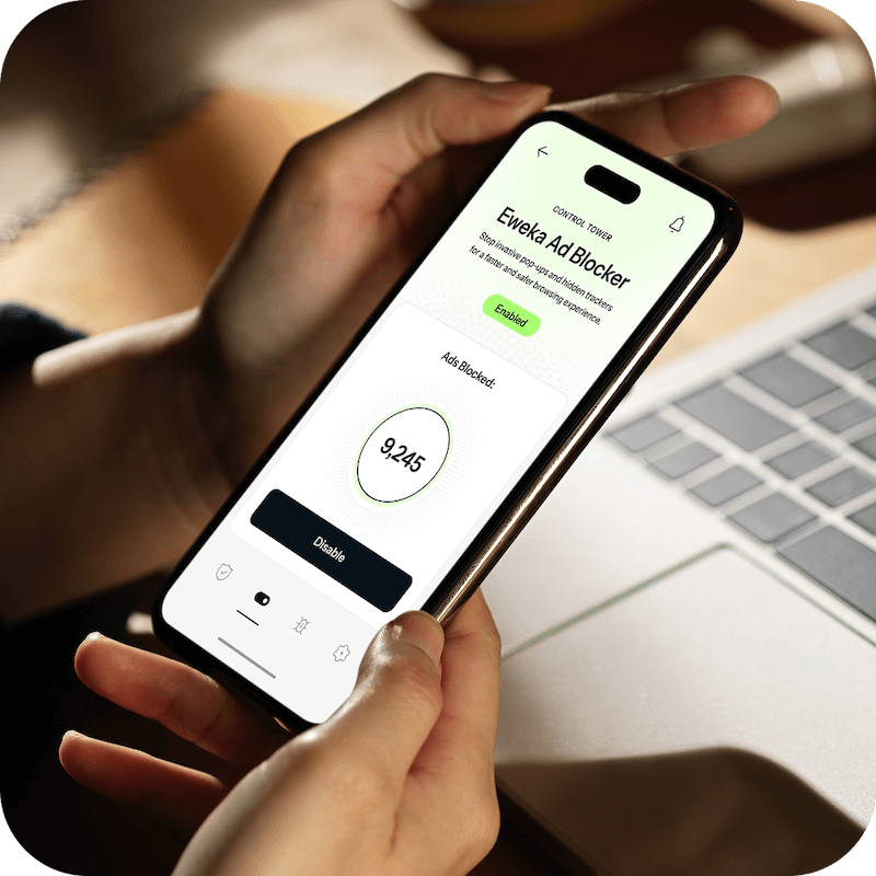 A pair of hands holding an open iPhone in front of a laptop, where the iPhone is connected to Eweka’s premium ad blocking settings for added protection and security.