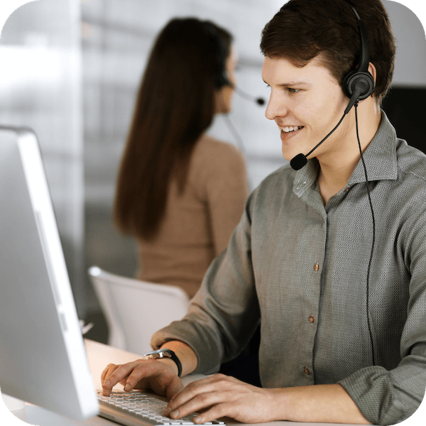 Un jeune représentant du support client travaille sur un ordinateur et parle avec un utilisateur d’Eweka, l’aidant à tirer le meilleur parti des serveurs DNS d’Eweka.