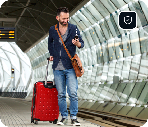 Un homme dans une gare tire une valise à roulettes tout en utilisant son téléphone pour se connecter au VPN premium d’Eweka, le meilleur VPN pour Usenet.