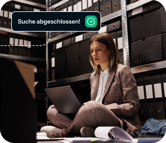 A woman sits cross-legged on the floor using a laptop in a room full of files, depicting the way that Eweka Internet Services offers access to a huge library of information from the Usenet daily feed.