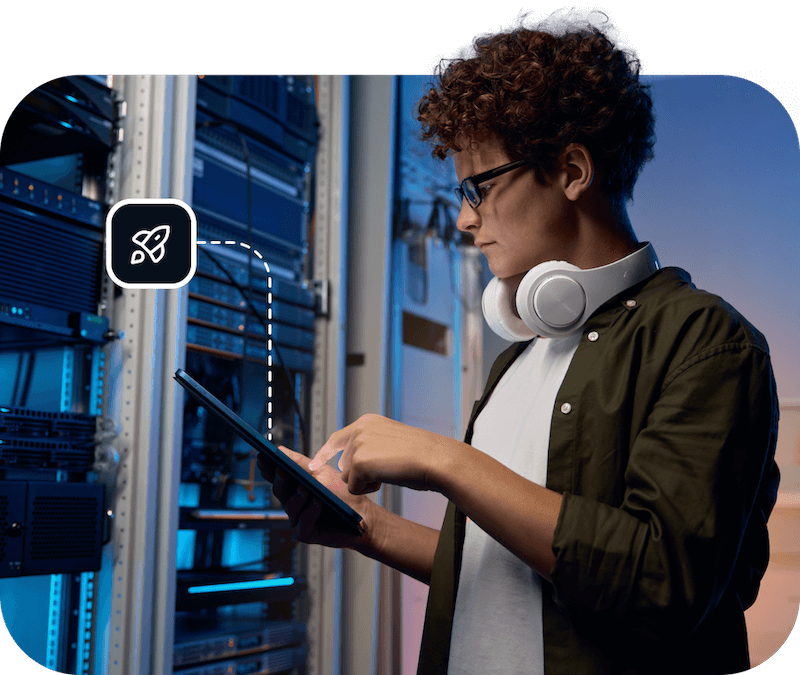 A young man wearing headphones works on a laptop in a Usenet server room, showcasing that Eweka offers the best DNS servers for users looking for more security.