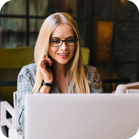 A female technical support agent is sitting in front of a laptop and using an earpiece to communicate with a customer.