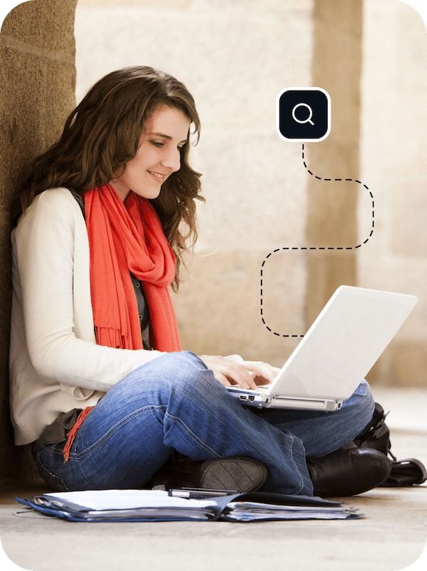 A young woman in an orange scarf sits on a floor using a laptop that is connected to Eweka so she can quickly and easily find exactly what she needs through Usenet.