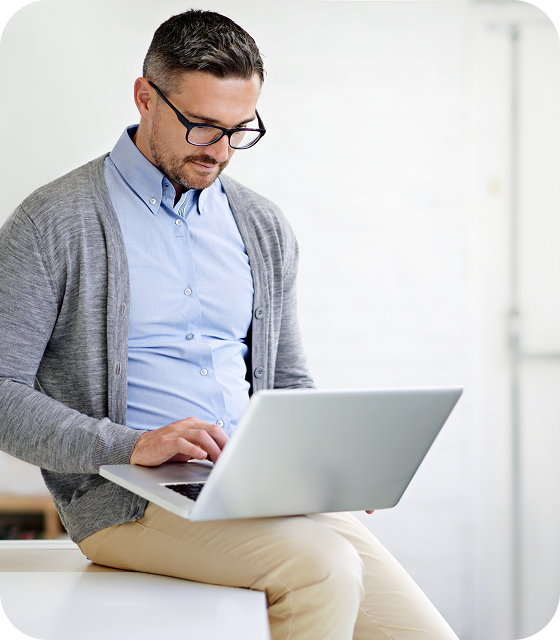 A man wearing glasses sits on an open laptop, accessing Usenet with Eweka’s secure SSL encryption settings.