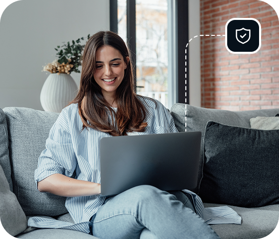A woman sits on a couch with an open laptop, safely browsing Usenet with the help of Eweka’s secure features and settings that enhance Usenet protection.