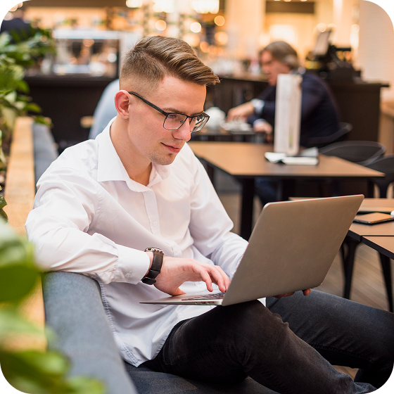 A man sits in a coffee shop, using a laptop to access Eweka, the top tier 1 Usenet provider, to access Usenet quickly and easily.