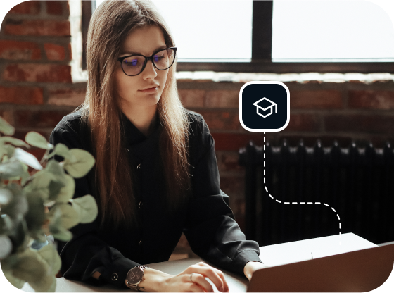 A woman in a black button-down shirt and black, cat-eye glasses is browsing Usenet on her laptop.